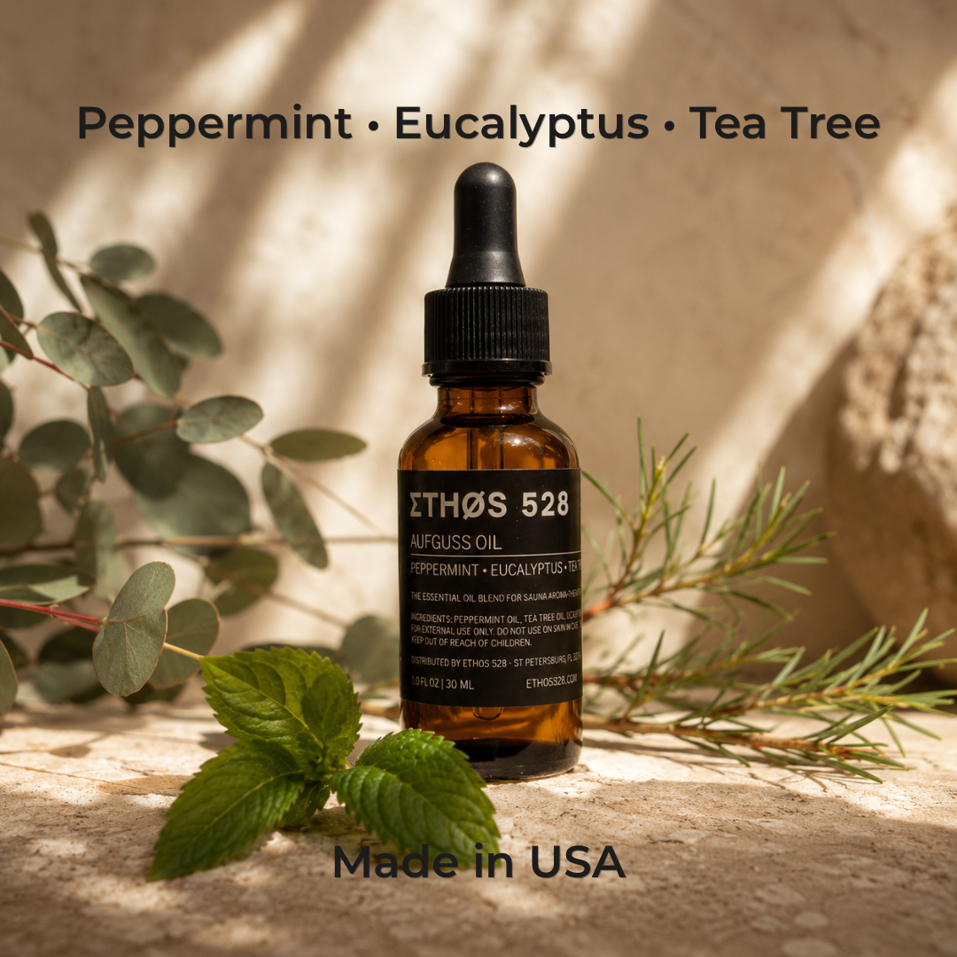 An amber glass dropper bottle labeled ETHΆS 528 AUFGUSS OIL, Peppermint + Eucalyptus + Tea Tree, styled with fresh mint leaves and pine branches on a textured stone surface with warm natural light shadows.
